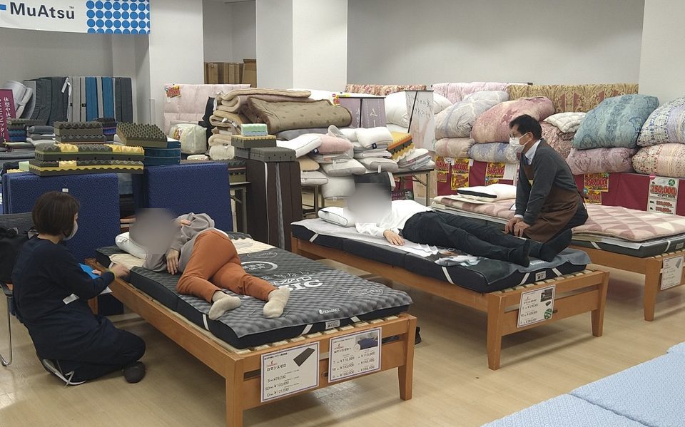 スタッフがお客さまに寝具をご案内する様子