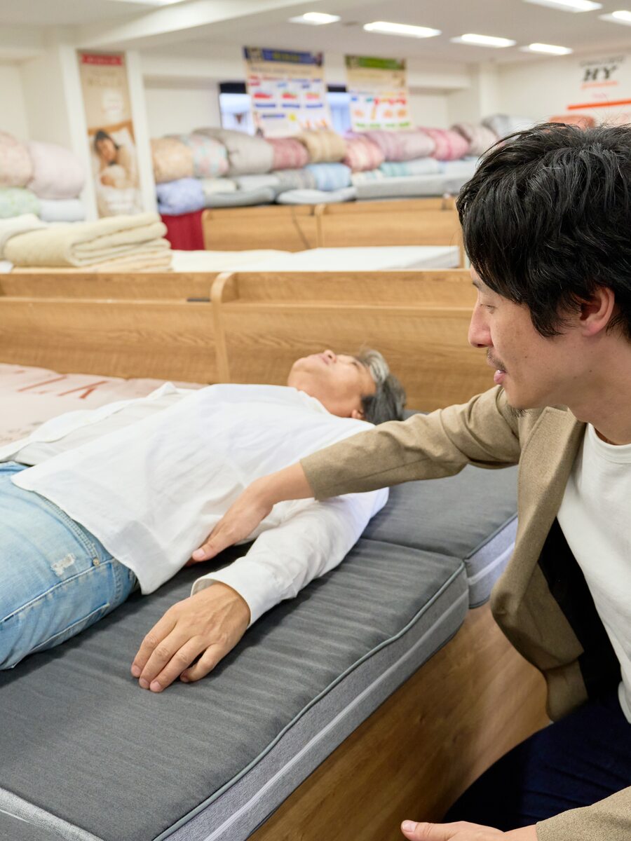 スタッフがお客さまの寝姿勢を確認しながらマットレスを寝比べていただいている様子