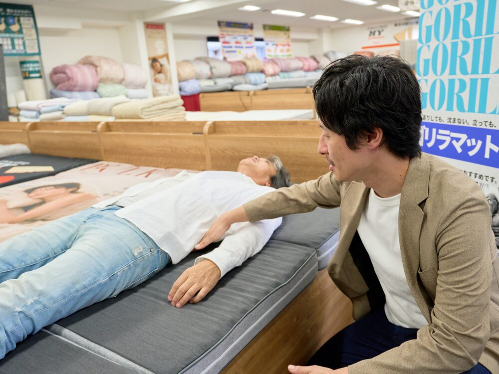 マットレスを寝比べるお客さまとスタッフ